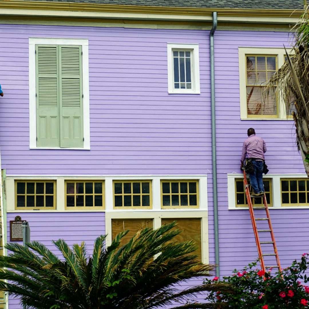 Painters on ladders painting the exterior of a house