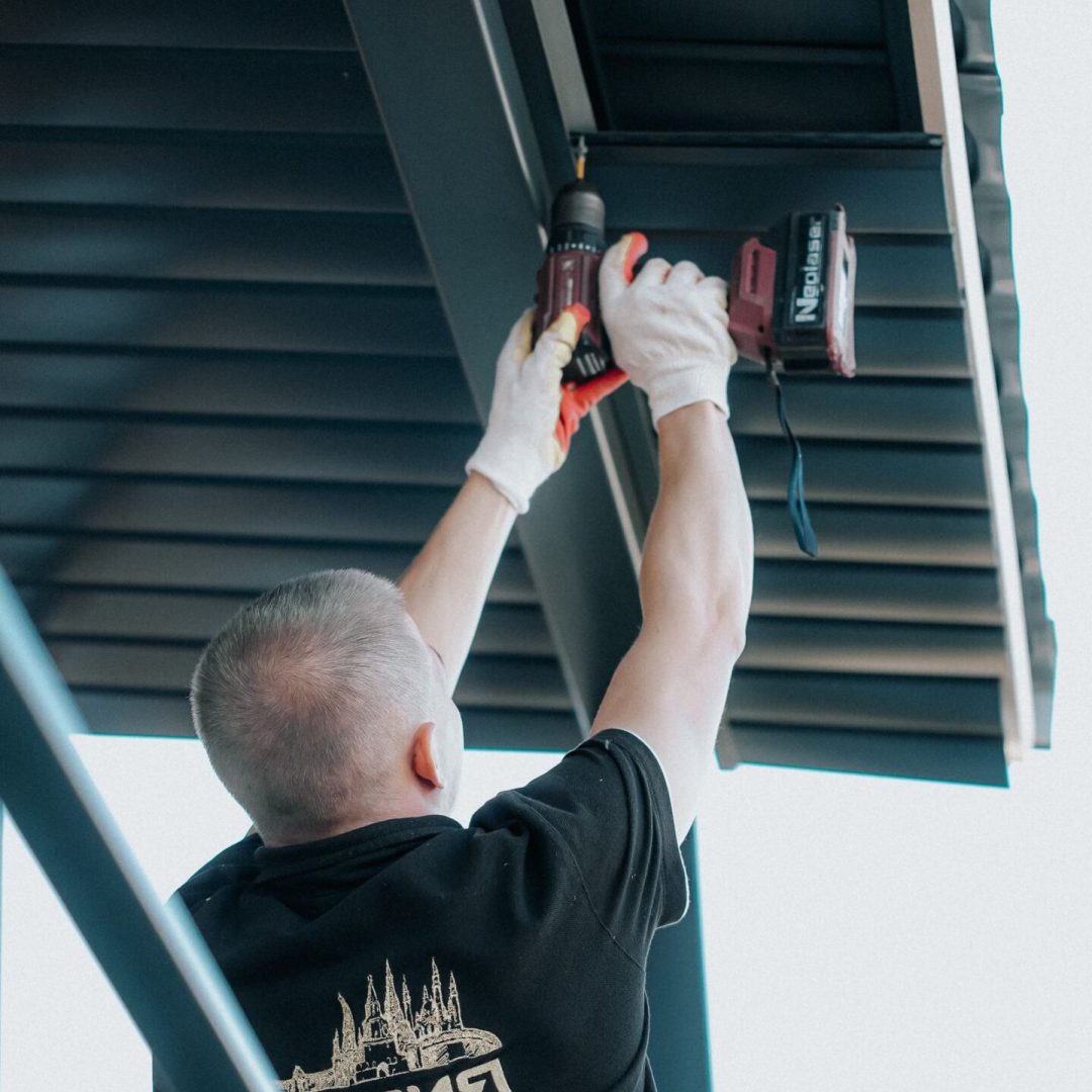 Contractor securing fascia and soffit with a drill