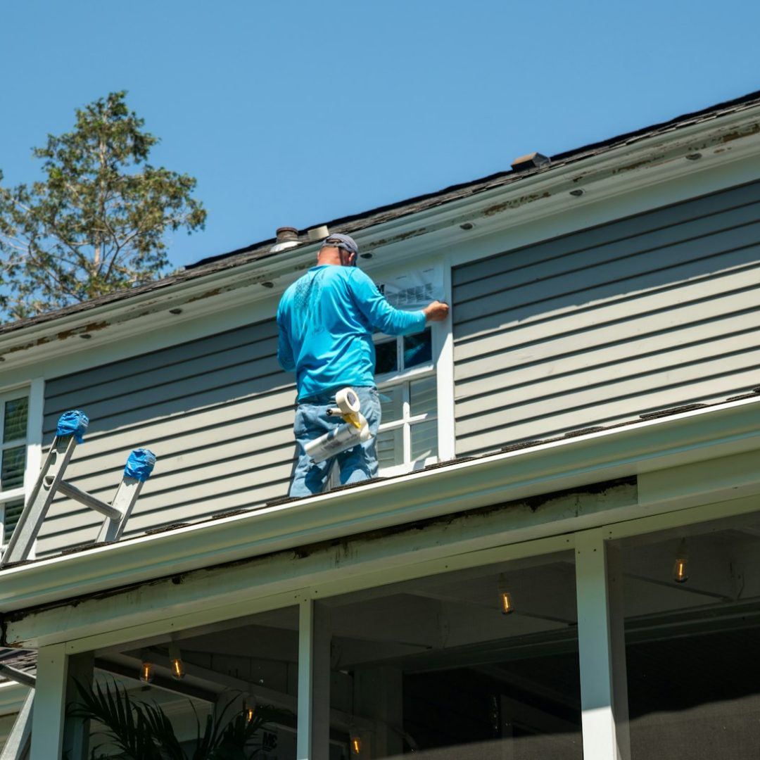 Worker installing siding trim at the roofline
